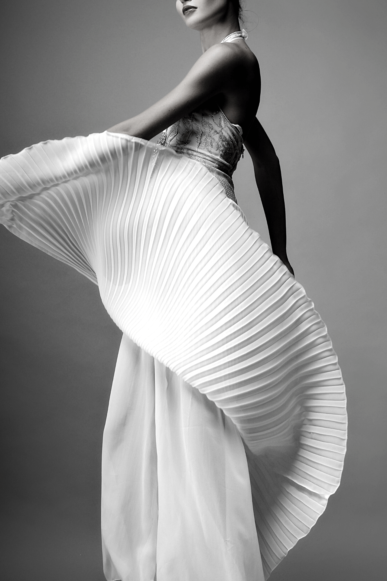 black and white image of a woman wearing a dress with a pleated skirt