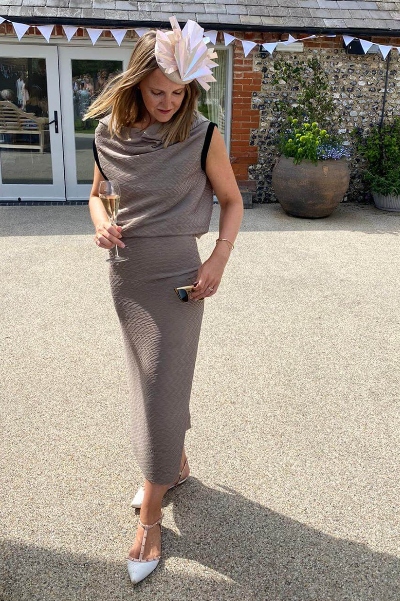 image of KARA HACKETT in a wedding outfit wearing a hat and taupe grey dress