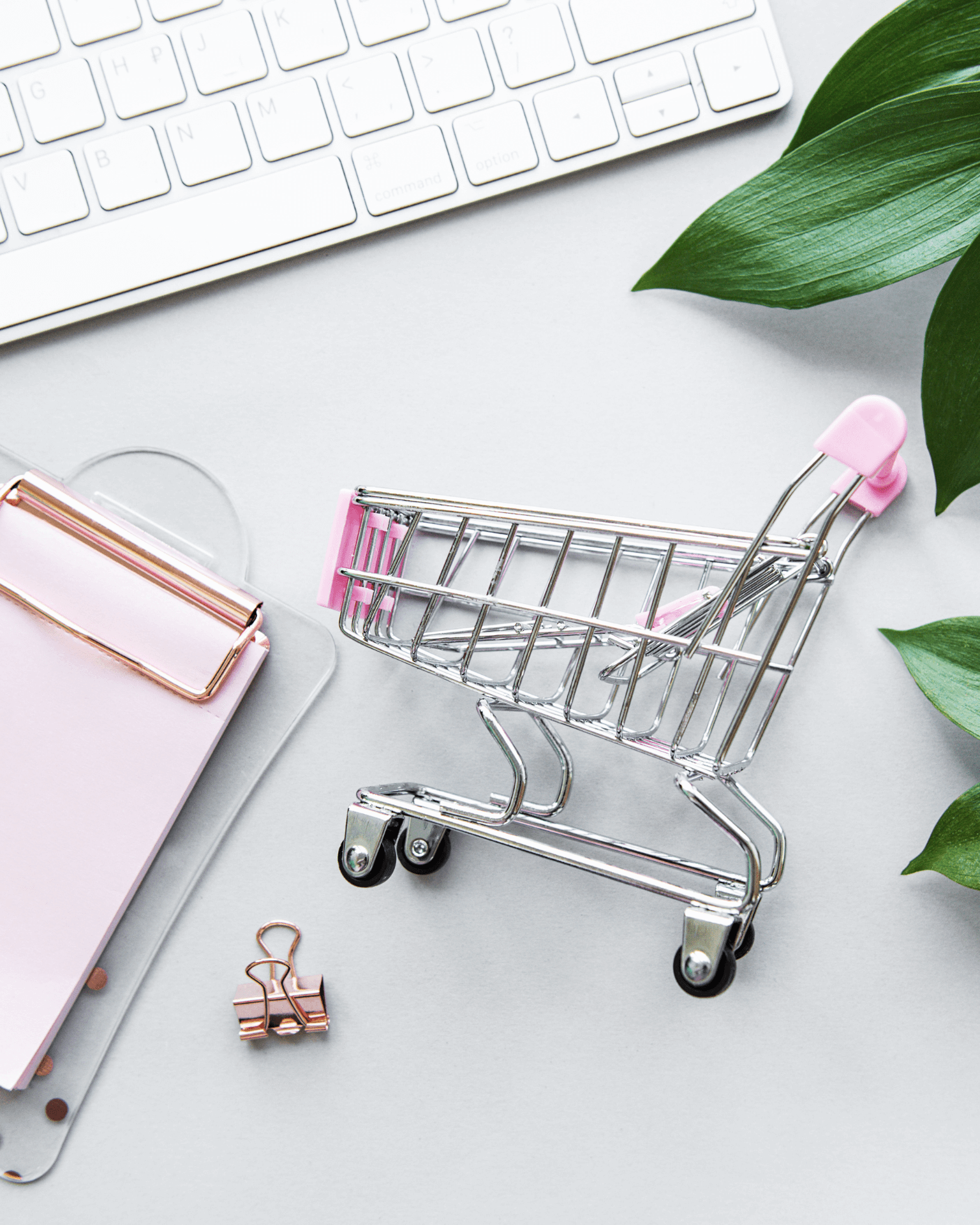 Image of a small shopping trolley next to a clip board and computer keyboard. 